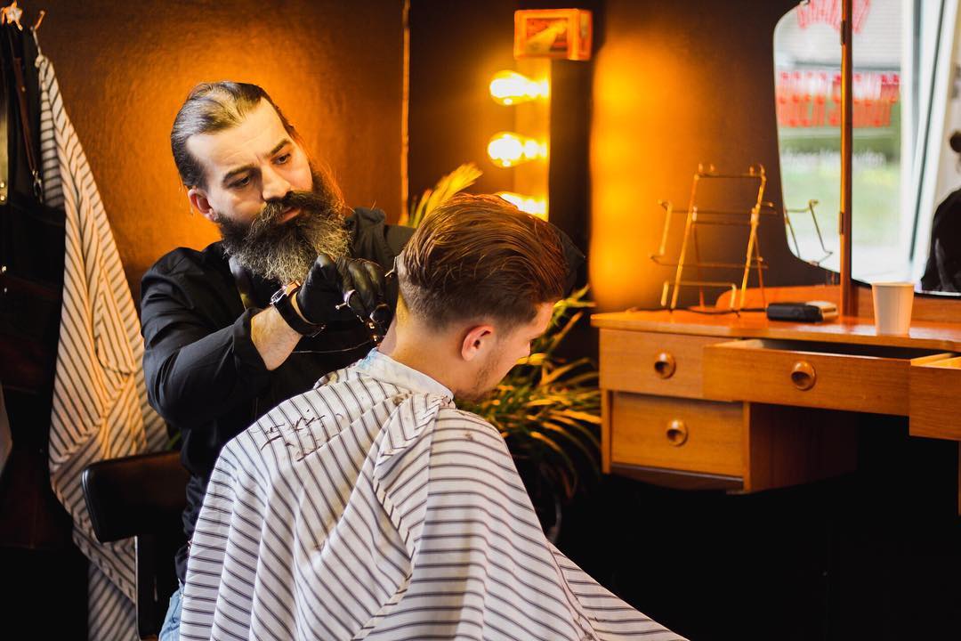 Rijad Ademi er master barber på Grand Barber Herrefrisør. Han er andregenerasjon barberer og driver en av norges eldste barbershops i Moss sentrum. Her jobber han fokusert med skinfade på en av sine kunder.